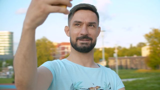 Portrait of smiling man shooting selfie while spinning on blurred background