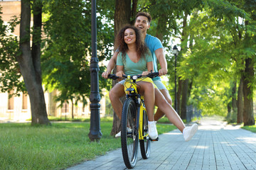 Naklejka premium Happy young couple riding bicycle on city street