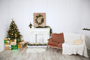 Interior in a classic style in a country house, decorated with decorative elements for Christmas. Artificial fireplace. Green christmas tree with gifts