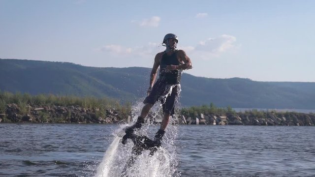 Flyboarding is a new extreme water sport. Athletic man performs tricks in flight. Spectacular sports coups and turns.