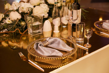 Wedding table setting with gilded cutlery and fresh flowers.