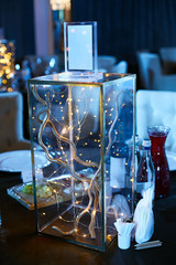 Wedding decor at a wedding ceremony. Glass square vase with branches and a luminous garland.