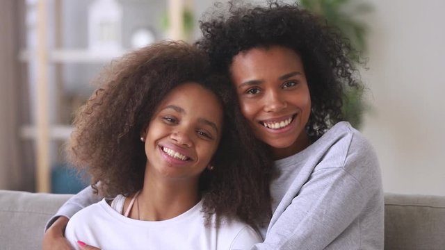 Mixed race mother embracing teenage daughter smiling looking at camera