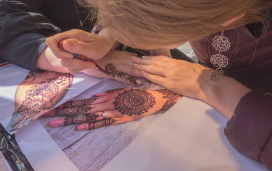 Master mehndi draws henna on a female hand