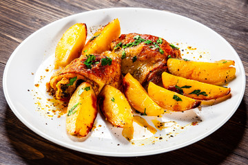 Grilled chicken thighs with baked potatoes on wooden table