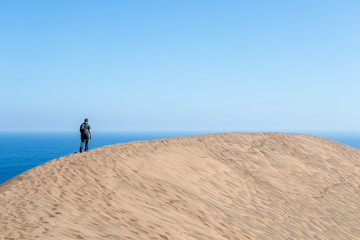 Young male hiker walking at Concon sand dune in Vina del Mar, Chile