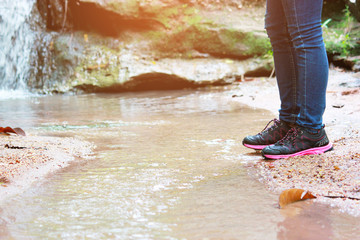A women Walking with jeans and sneaker shoes and Waterfall background, concept travel, soft and select focus.