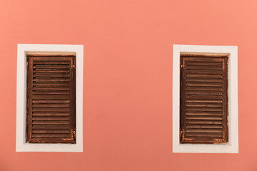 Two windows with old wooden shutters on a fresh-painted wall