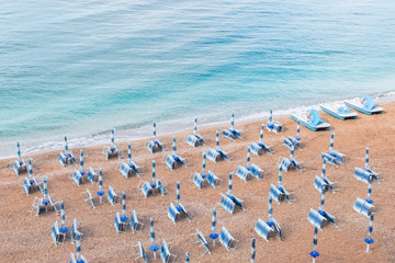 Empty beach with sunbeds and parasols is waiting for guests. View from above.