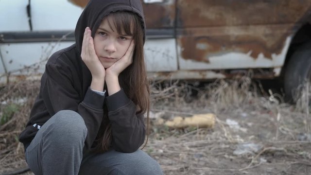 Childhood in loneliness. Homeless children in a landfill. Sad little girl sits in a junkyard.