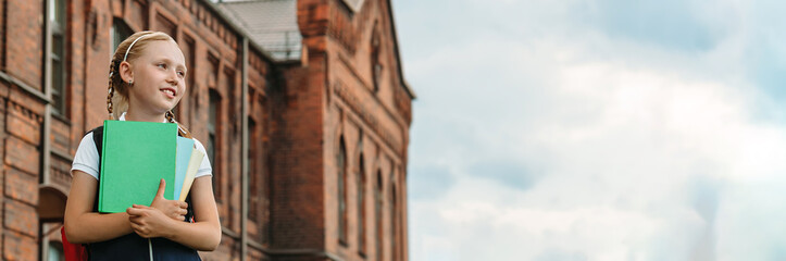 Portrait of a young girl in a school uniform with books in her hands. Against the background of an old college.