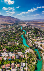 Aerial panorama view of Kibbutz Nir David in Northern Israel with the turquoise color Amal river and the surrounding agricultural land  
