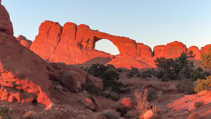 Stunning window formation in Arches National Park glowing in red light at sunset - Powered by Adobe