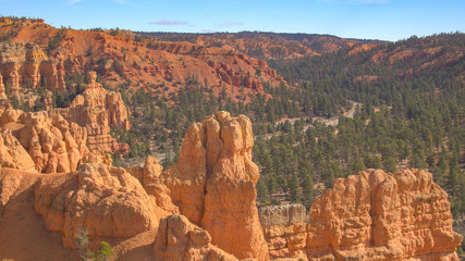 AERIAL: Flying over red rocky cliffs revealing car entering Bryce Canyon NP Utah