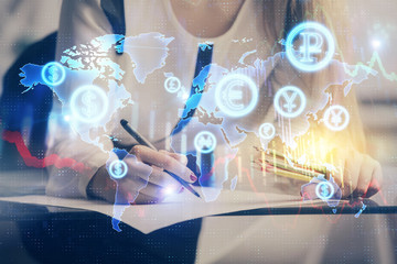 A woman hands writing information about stock market in notepad. Forex chart holograms in front....