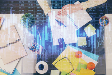 Hand taking notes in notepad. Forex chart holograms in front. Concept of research. Double exposure