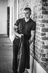 Young handsome sporty man in business suit on a background of a brick wall in the summer. Black and white shot.