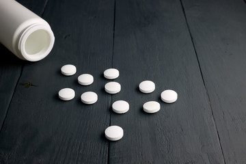 Medicine pills, drugs, capsules, vitamins and open white bottle on a dark wooden background.