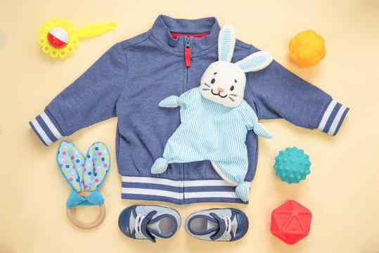 Baby Toys, Boots And Clothes On A Orange Flay Lay Background.