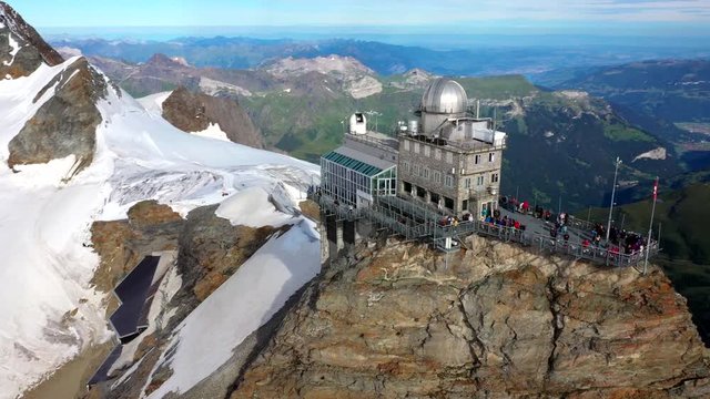 Sphinx Observatory, Aerial, rising, drone shot, around the a building on the top of Europe, at Jungfraujoch, in Bernese Alps, on a sunny day, in Switzerland