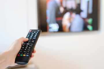 A hand pointing a remote control at the TV
