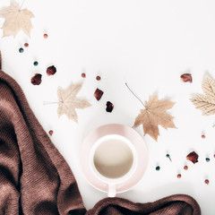 Autumn home cozy composition. Cup of coffee, knitted plaid, dried autumn leaves, berries, flowers on white background. Fall background. Flat lay, top view, copy space, square
