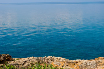 sea horizon with rocky shore cliffs and sun light blue sky background. Sea waves crashing on rocks, Samed, Thailand