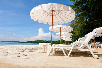 Lounge chairs with sun umbrella on a beach. Sun of summer time on sky and sand of beach relaxation landscape viewpoint. Ocean nature tranquility, Thailand.