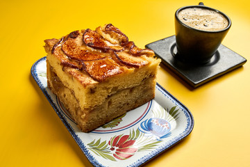 apple cake with black coffee on yellow table