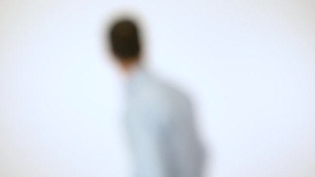 A man against the white background is lost, looks around in confused panic - blurred - white screen studio