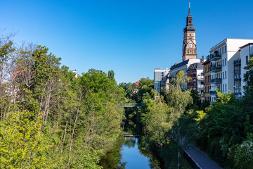 Picture from the Karl Heine Canal in the scene district Plagwitz in leipzig between center and lindenauer harbor with bike path, old and modern houses and church