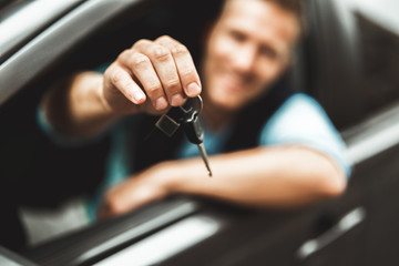 young handsome man feels happy holding keys from his new car © studioprodakshn