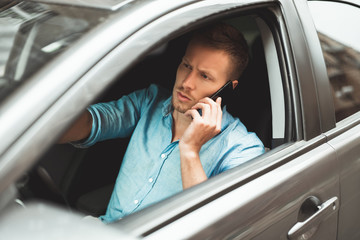 young handsome man drives unsafely speaking on his smartphone on the run