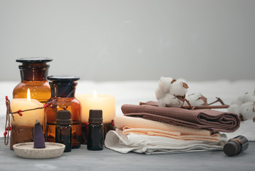 Aromatherapy oil bottles, towel and burning candles on a wooden table. Spa concept background.