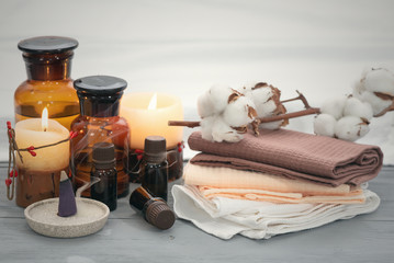 Aromatherapy oil bottles, towel and burning candles on a wooden table. Spa concept background.