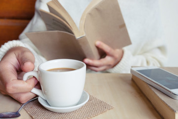Relaxing moments , Cup of coffee and a book on wooden table in nature background, color of vintage tone and soft focus, winter morning concept.