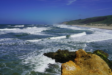 Blue sky, white ocean waves and sunshine sandy beach at Pacific Coast, California