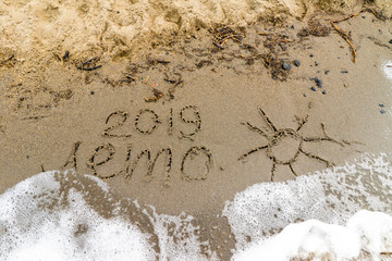 sandy beach with a wave runs onto the word summer - leto 2019