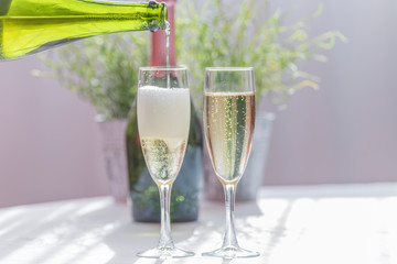 Filling two glasses with tasty and bubbly cava, a vase and a green bottle of cava on the bottom. Wedding concept