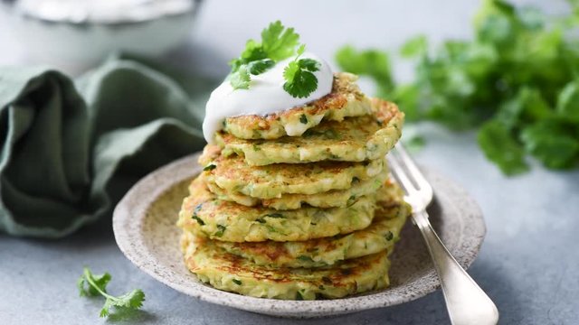 Healthy zucchini fritters with sour cream. Stack of vegetarian vegetable fritters or pancakes. Clean eating concept
