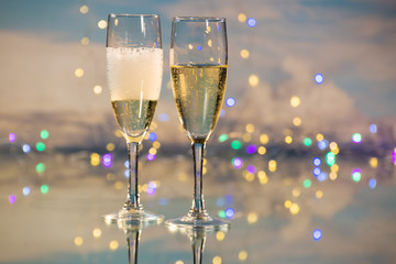 Sparkling champagne and yellow cava served in two glass cups with the background illuminated by many small Christmas lights. Concept of party and celebration.
