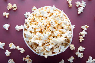 Testy warm popcorn viewed from above on red background. Top view. Enterteinment concept