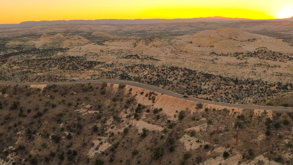 AERIAL: Black SUV car traveling along the mountain ridge road at golden sunrise