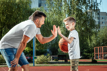Father and son play basketball together at the basketball court. father spends time with the child,...