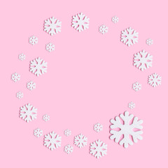 Winter composition of snowflakes on pastel pink background. Flat lay, top view.