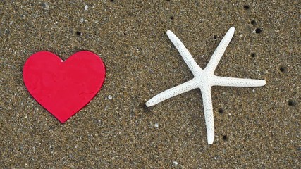 Heart shapes end starfish on sandy beach.