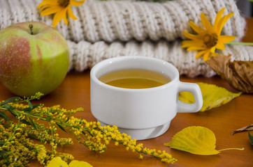 cup of tea, apple, flowers and a scarf. Autumn concept.