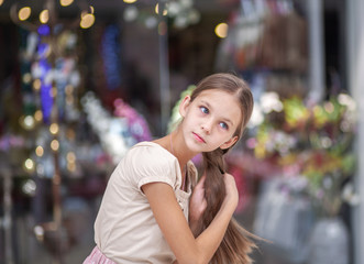A beautiful young girl stands at the storefront and straightens her hair.
