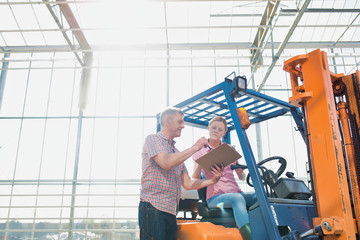 Young woman driving forklift while senior talking to senior in greenhouse © MDBPIXS