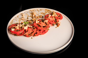 top view on sliced tomato exquisite decorated with assorted herbs